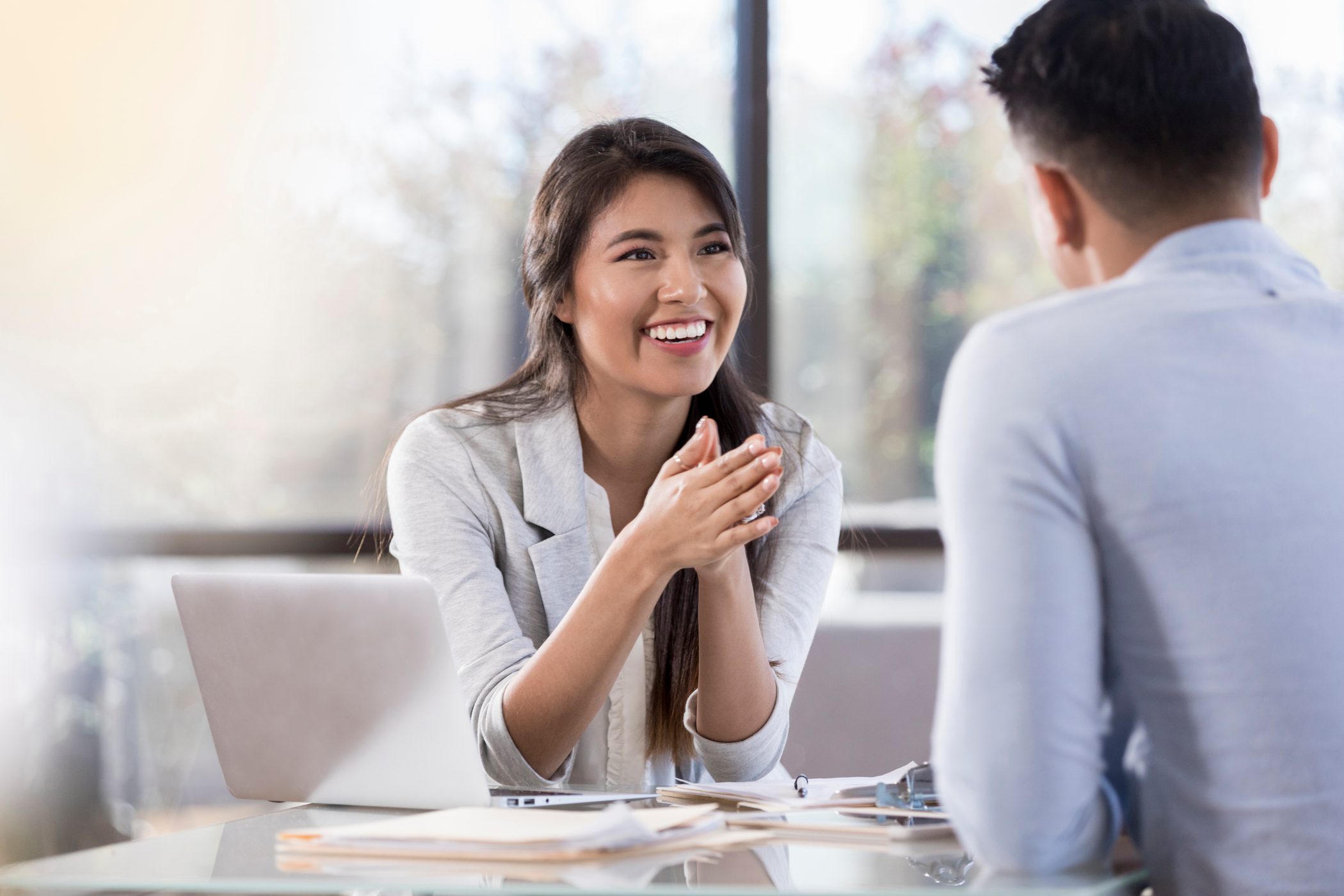 A female psychiatrist smiles broadly as she speaks to her partially unseen male patient.