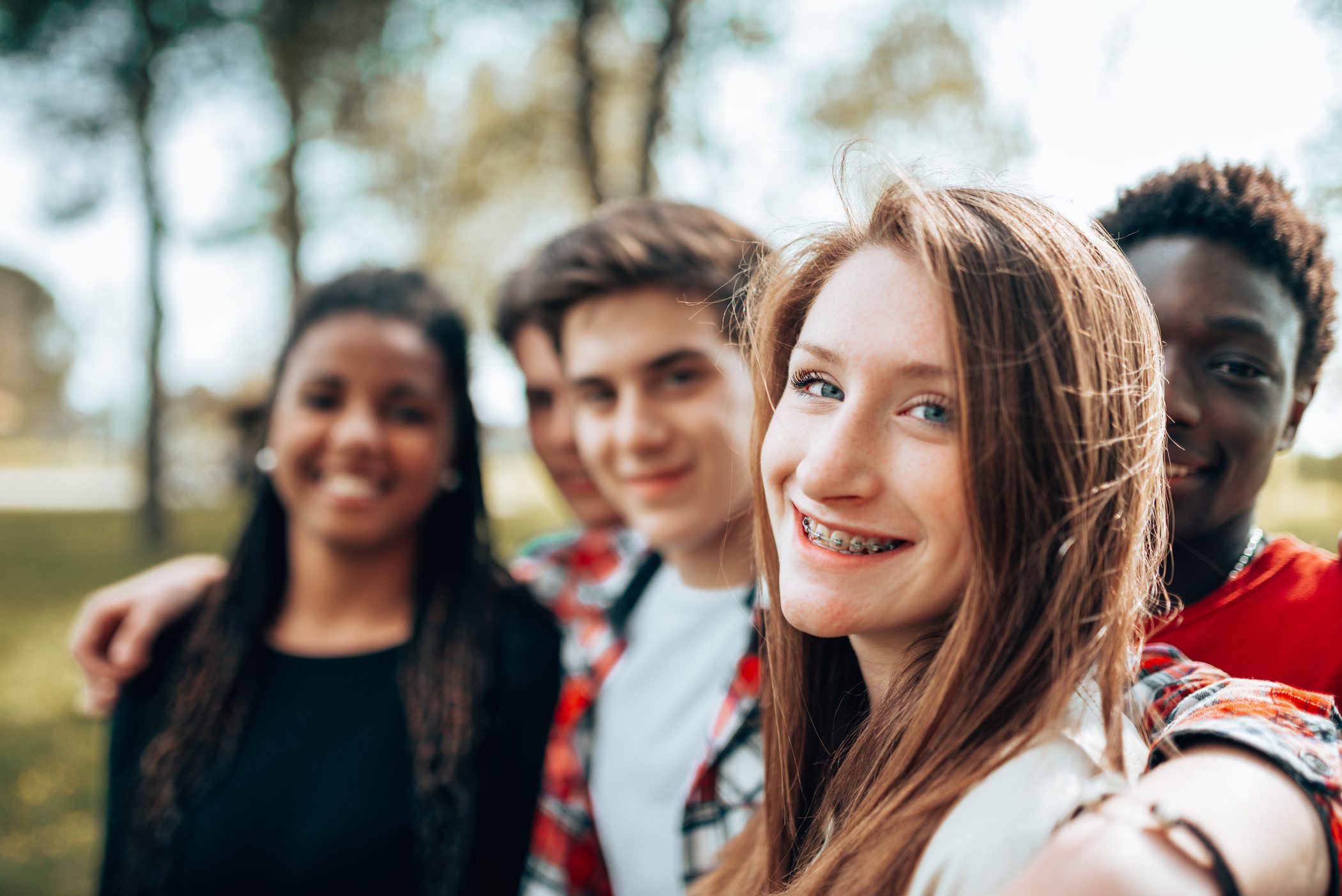 A teenage girl surrounded by her peers smiles for a picture.