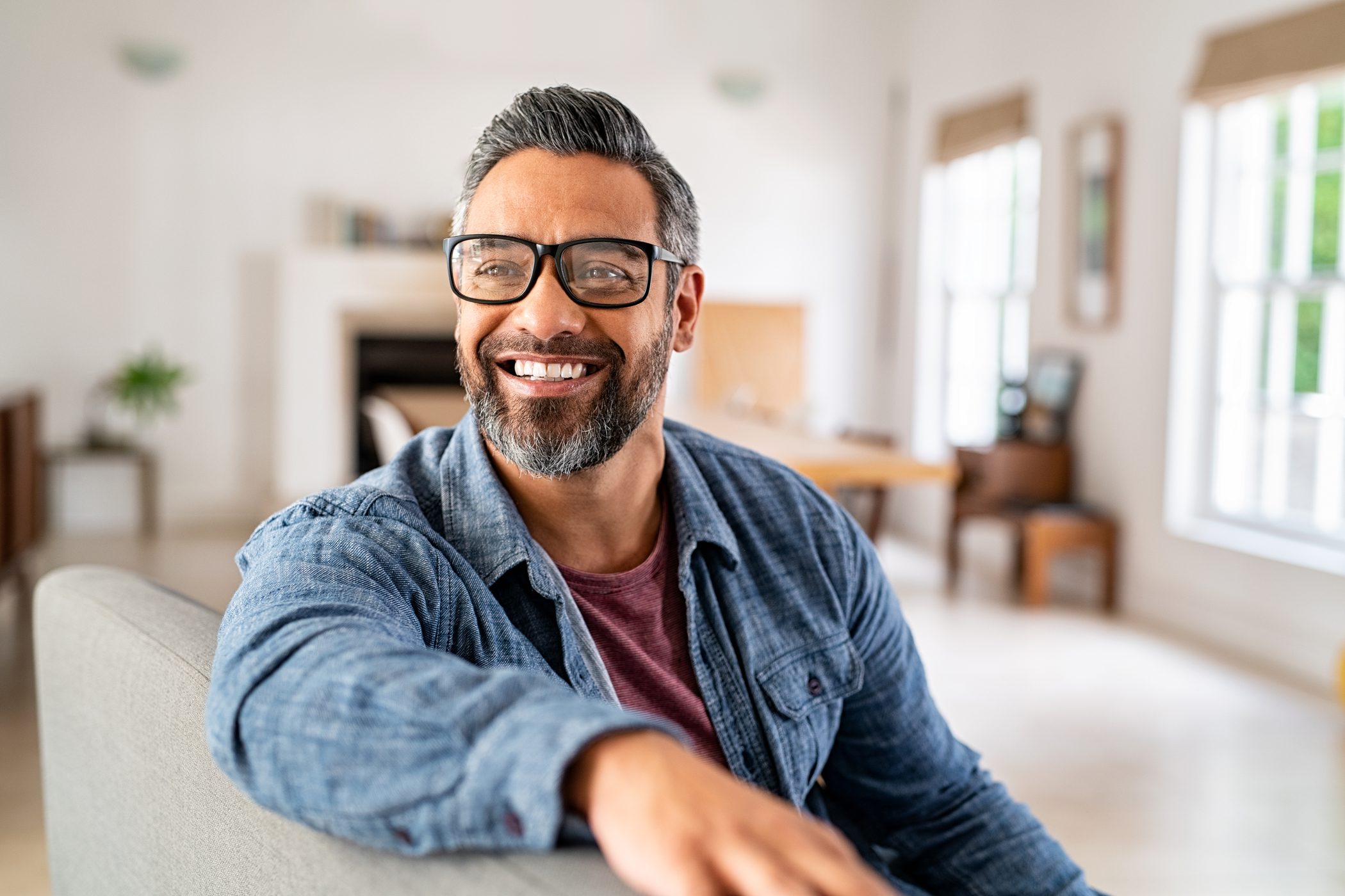 An adult man sits in an office, smiling broadly.